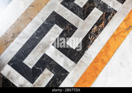 Old style stone mosaic floor tiling with yellow black and white geometric pattern, background photo texture Stock Photo