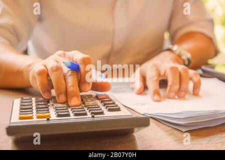 Businessman analyzing investment charts using calculator for profit and loss. Stock Photo
