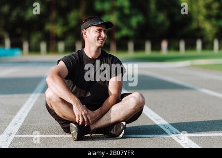 Young handsome guy smiles while sitting on the floor Stock Photo