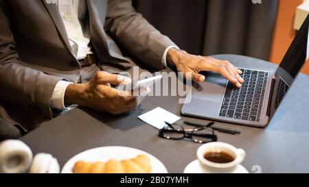 Cropped image of afro guy using phone and computer Stock Photo
