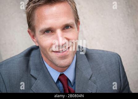 Portrait of businessman standing outdoors smiling at the camera in a head and shoulders close-up Stock Photo