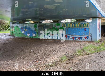 Footpath under a road bridge with a painted mural or artwork showing the town of Arundel in West Sussex, England, UK. Stock Photo