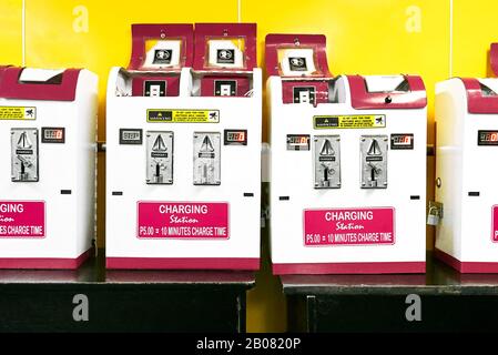 Simple colorful pay cellphone charging stations standing on a table inside a tourist travel area, used by travelers, seen in the Philippines, Asia Stock Photo