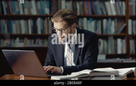 Businessman typing laptop in library Stock Photo