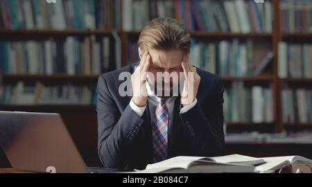 Stressed businessman sitting in library Stock Photo