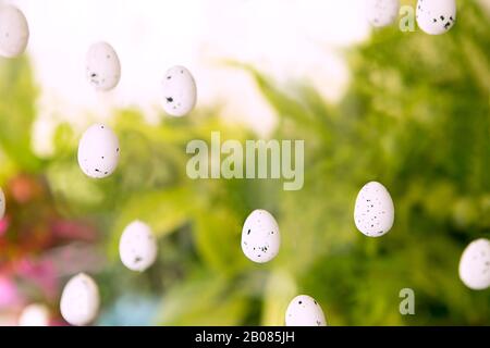 Easter backdrop. Easter eggs in the air on green spatial background. Abstract decoration, of white hovering eggs with black spots seasonal arrangement Stock Photo