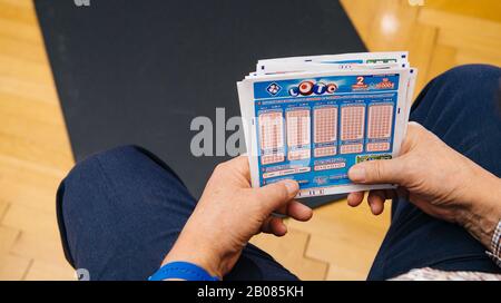 Paris, France - Apr 2, 2019: Overhead view of senior male hands holding Loto tickets from the FDJ French lottery system Stock Photo