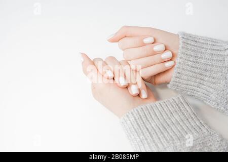 Stylish manicure on young woman on nails, color light pink, white background Stock Photo