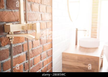 Modern shower system copper color for bathroom in loft style, brick wall. Sunlight window Stock Photo