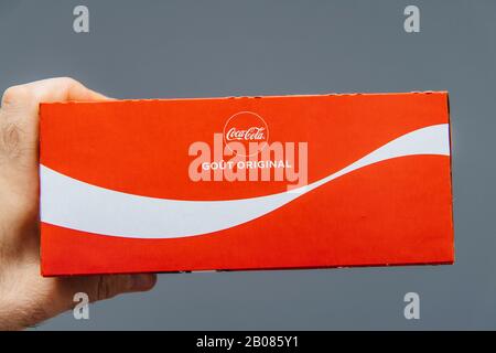 Paris, France - Jul 20, 2019: Man hand holding against gray background pack of Coca-Cola sweet drink pack - French edition with Original taste inscription Stock Photo