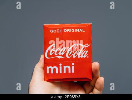 Paris, France - Jul 20, 2019: Man hand holding against gray background pack of Coca-Cola sweet drink pack - French edition with Original drink inscription Stock Photo