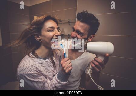 Couple morning routine. Man and woman sharing bathroom. Shaving beard and brushing teeth. Starting the day in a great mood Stock Photo