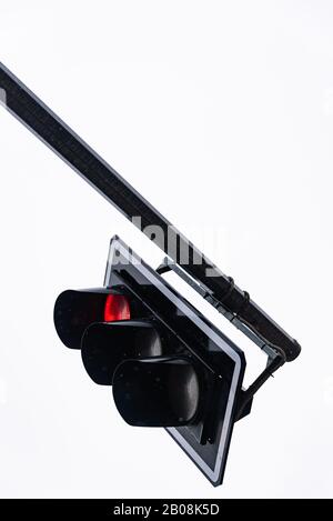 Detail of a traffic light with red light on. View of a black supporting structure against a clear white sky Stock Photo