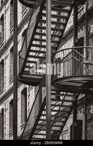 Exterior metal stairs of an old restored factory in warm black and white Stock Photo