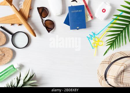 Summer composition with hat, sunglasses, palm leaf, pineapple, passport, boarding pass and others on white wooden background top view. Summer travel c Stock Photo