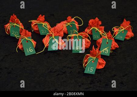 Twenty four little presents wrapped in red, green tags golden numbers from 1 to 24 on black as self made advent calendar - 15th of December Stock Photo