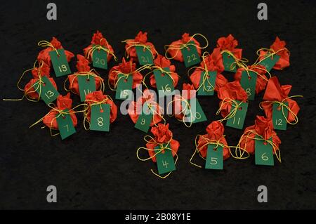 Twenty four little presents wrapped in red, green tags golden numbers from 1 to 24 on black as self made advent calendar - 4th of December Stock Photo