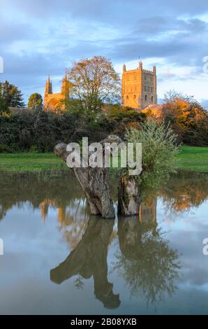 Tewkesbury Abbey, in Worcestershire lit by the setting sun at golden hour during and reflecting in the floodwater of the 2019 floods Stock Photo