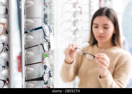glasses in store and beautiful woman out of focus choosing glasses Stock Photo