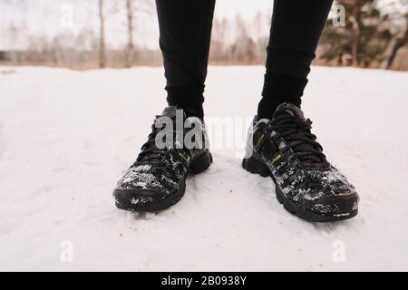 Close-up of unrecognizable person in winter black sport shoes standing on snow Stock Photo