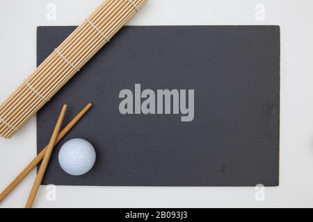 Rectangular slate plate with chopsticks for sushi and golf ball. Golf Design Stock Photo