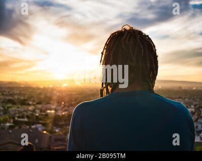 Unrecognizable man with dreadlocks admiring nature during sunset Stock Photo