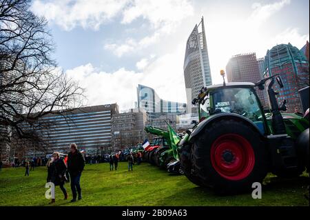 Farmers walk around the tractors parked on the grass during the protest.Thousands of Dutch farmers under the motto 'all brakes off' are protesting against the measures proposed to cut down on nitrogen emissions at the Malieveld, in The Hague. The Mesdag Fund has instructed the University of Amsterdam to start a three-year study into the precipitation of nitrogen in nature reserves and to find out exactly where nitrogen emissions from livestock farms end up. After several meetings with the Dutch government, farmers keep waiting for a solution of the nitrogen problem. The nitrogen debate in the Stock Photo