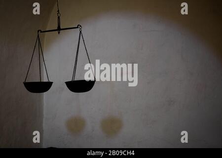 Old hanging scale as a symbol of justice, representing threat in a dark room. Stock Photo