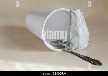Spoon with the remains of the dairy product inside the fallen glass. Kitchen table after breakfast. Eye level shooting. Selective focus. Stock Photo