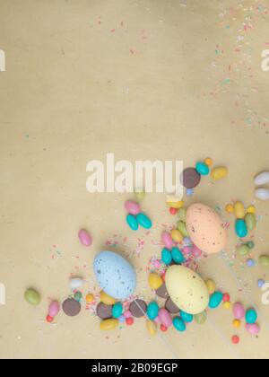 Blurred Colorful Easter eggs, multi - colored sweets on yellow background. Copy space, toned Stock Photo