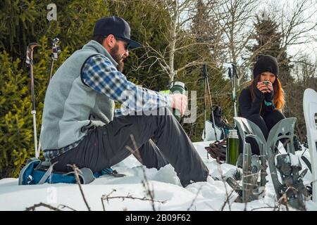 Travelers rest in the winter in the mountains. The guy with the girl on a halt. Snowshoeing Stock Photo