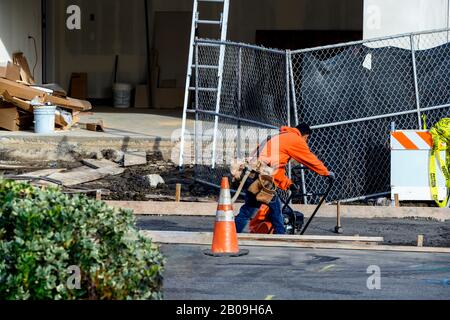 Concrete construction contractors installing a sidewalk, curb and storm drainage gutter on a new house construction. Stock Photo