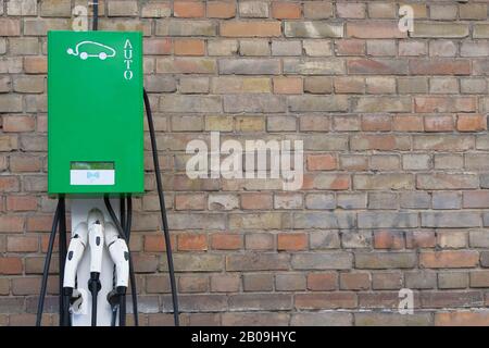 Electric cars charging concept. Electric vehicle charger station installed on vintage brick wall. Modern technology and old buildings. Stock Photo