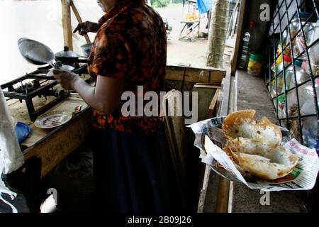 Hopper Making - Hopper, locally known as ‘Appah’ is a popular and common food in Sri Lanka. It is widely eaten as snakes as well as meal through out the day from breakfast to dinner. The thin edge of the bowl shape is crispy and the bottom is soft. Hopper is mainly made of rice flower and coconut milk; some spices are also added for taste. There are two types of hopper one plain Hopper and Egg Hopper. For Egg Hopper egg is spread over during preparation. It is usually taken with red chilli and onion pest. Suburb of Colombo, Sri Lanka. June 22, 2007. Stock Photo