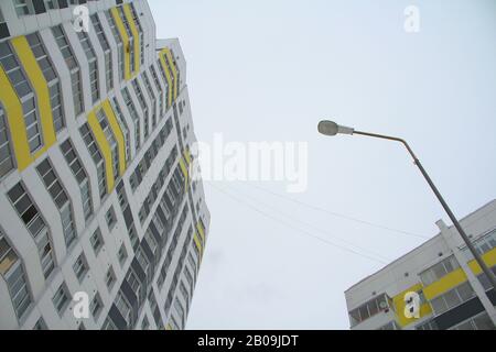 Modern brick multi-storey building, tiled in white, decorated with dark gray and yellow panels. The concept of acquisition of new housing, and level of housing conditions, modern urban architecture Stock Photo