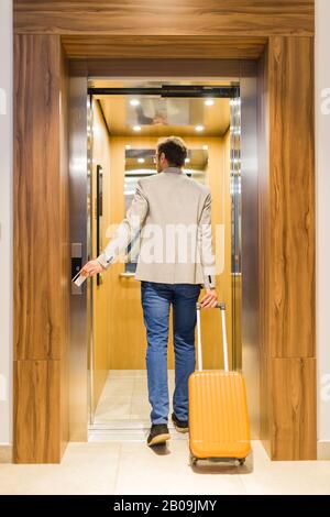Modern businessman entering the elevator with luggage. Business and travel concept. Stock Photo