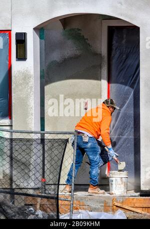 Construction worker putting decorative plaster on house exterior Stock Photo