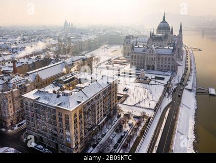 Budapest, Hungary - Aerial view of the snowy riverside of Pest with Parliament of Hungary and St.Stephen's Basilica on a misty winter morning Stock Photo