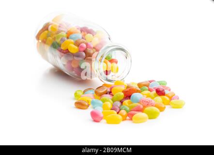 Fruity jellybeans. Tasty colorful jelly beans in glass bottle isolated on white background. Stock Photo