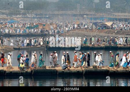 Devotees walk across makeshift bridges to participate in the annual Bishwa Ijtema on the bank of the Turag river in Tongi. Bishwa Ijtema is the largest Muslim Pilgrimage after Haj, in which several million Muslims from around the world take part. Tongi, Dhaka, Bangladesh. January 31, 2009. Stock Photo