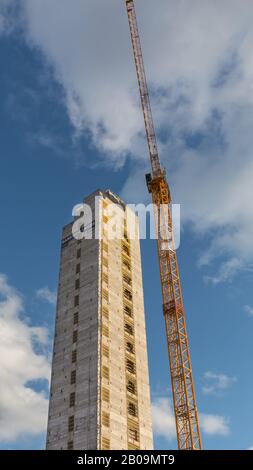 Concrete elevator shaft tower and crane,  tall building under construction with marked storeys against sunny blue sky, Bankside Yards, UK Stock Photo