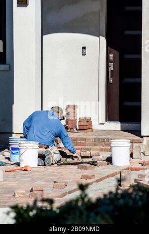 Masonry construction worker laying a brick walkway and front porch. Stock Photo