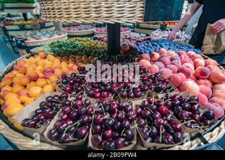 Fruit basket divided on one side the cherries, on the other the peaches of various types and plums. Stock Photo