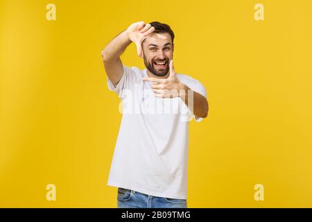 Handsome Irish redhead man with beard wearing glasses over yellow isolated background smiling making frame with hands and fingers with happy face. Stock Photo