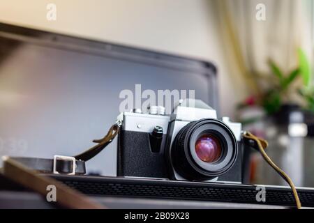 Vintage analog film camera on a laptop on a wooden table Stock Photo