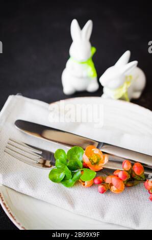Easter table setting with spring flowering branches, cutlery and decorative rabbits. Spring Easter background for menu. Holidays background with copy Stock Photo