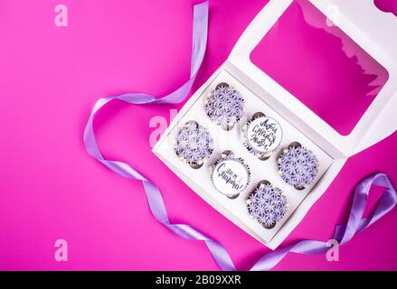 Delicious shawn cupcakes with curd cream in the form of flowers on a pink background. White cupcake packaging. Stock Photo