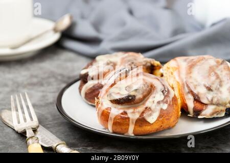 Cinnamon danish bun or cinnabons on dark background with coffee cup. Sweet homemade pastry. Stock Photo