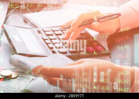 Close up side view of a girl’s hands holding a cash receipt and using a calculator. Online trading, market and profit analysis, risk calculation, stoc Stock Photo