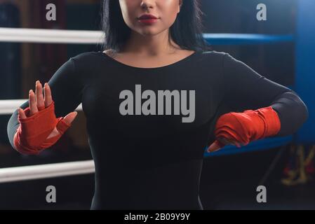 Boxer woman hands with red boxing wraps in the boxing ring. Closeup Hands of Female Fighter Wearing Boxing Bandages Preparation. The concept of female Stock Photo